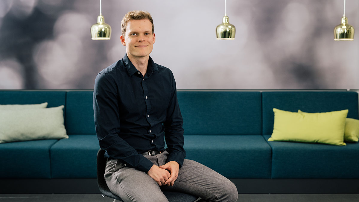 Mies istuu sohvalla ja katsoo kameraan.